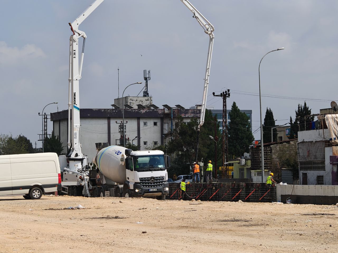 Concrete mixer trucks and construction workers at an urban building site.
