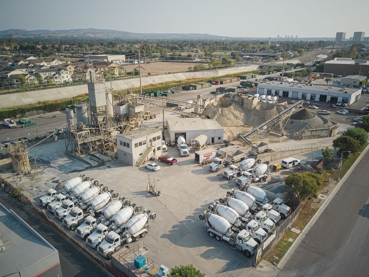 Aerial shot of a bustling cement manufacturing plant with mixer trucks and industrial equipment.